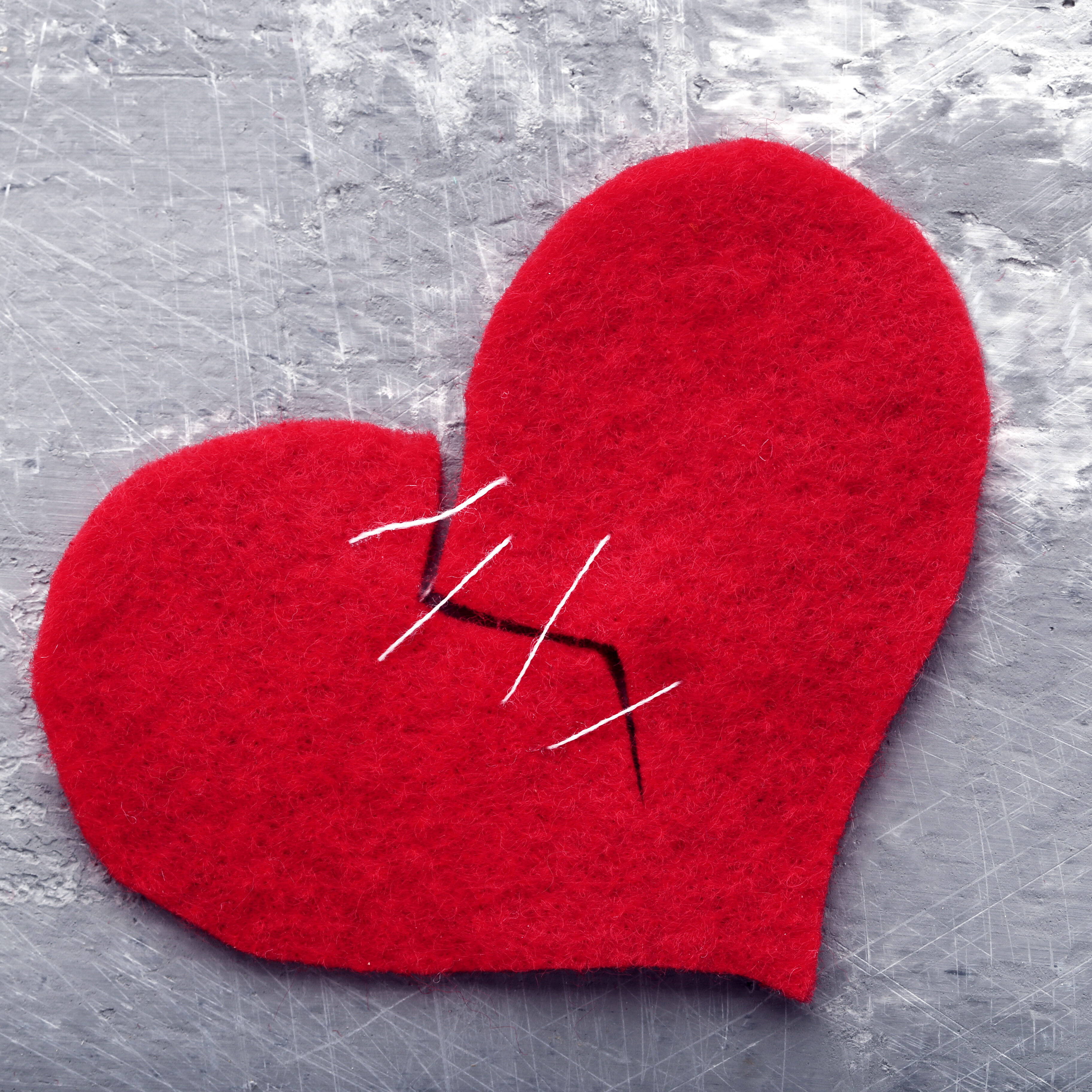 Broken red heart on grey wooden table